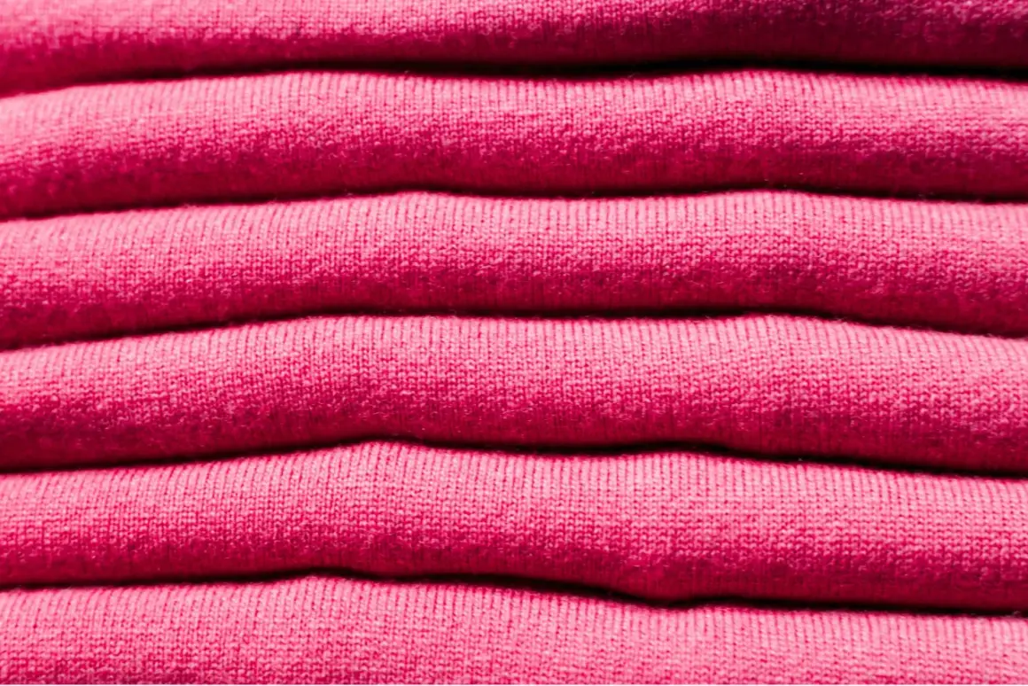 Una pila de ropa de franela rosa, suave y acogedora, lista para abrigarte.