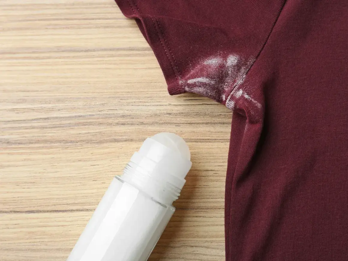 Manchas blancas de desodorante en una camiseta granate, un problema común que puede desteñir ropa.
