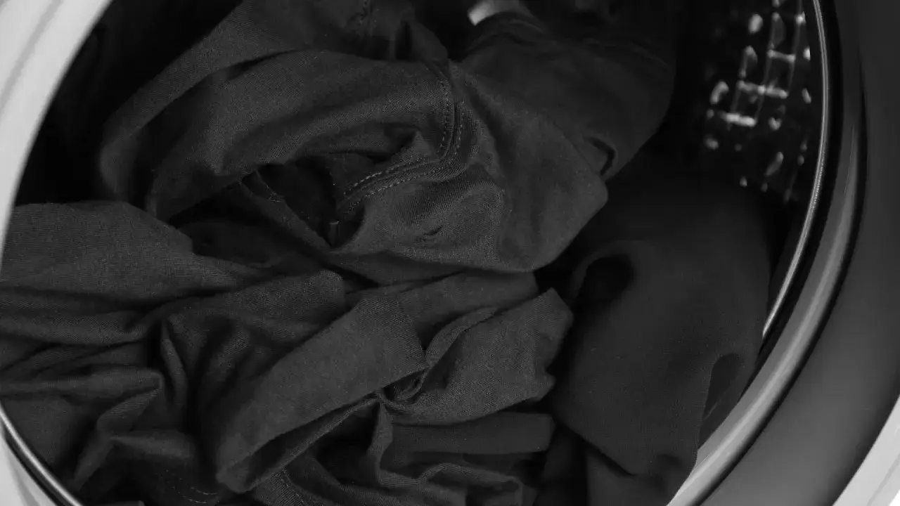 Ropa oscura arrugada en la lavadora, lista para recuperar su color.