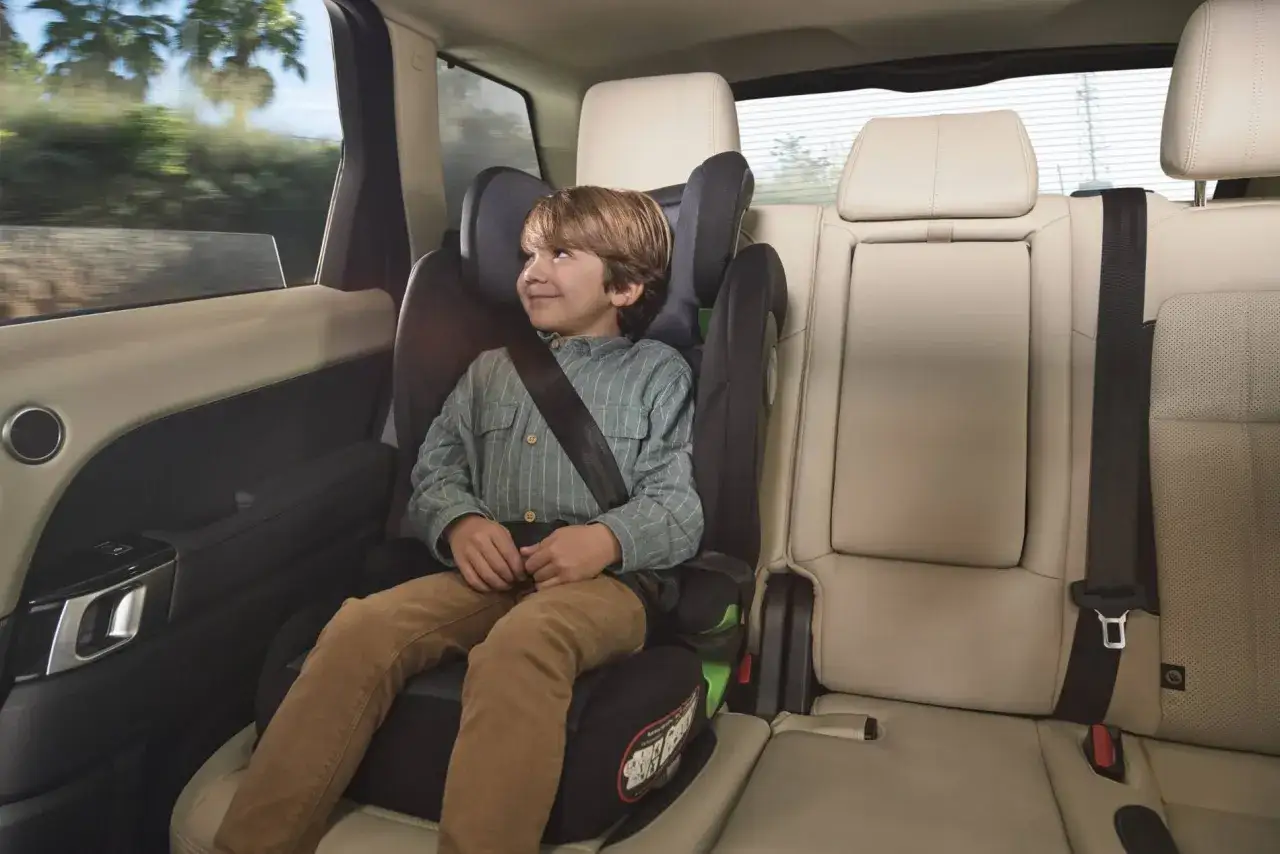 Ni&ntilde;o sonriente en silla de auto, viajando seguro. La pregunta es hasta que edad los ni&ntilde;os deben usar silla de auto.