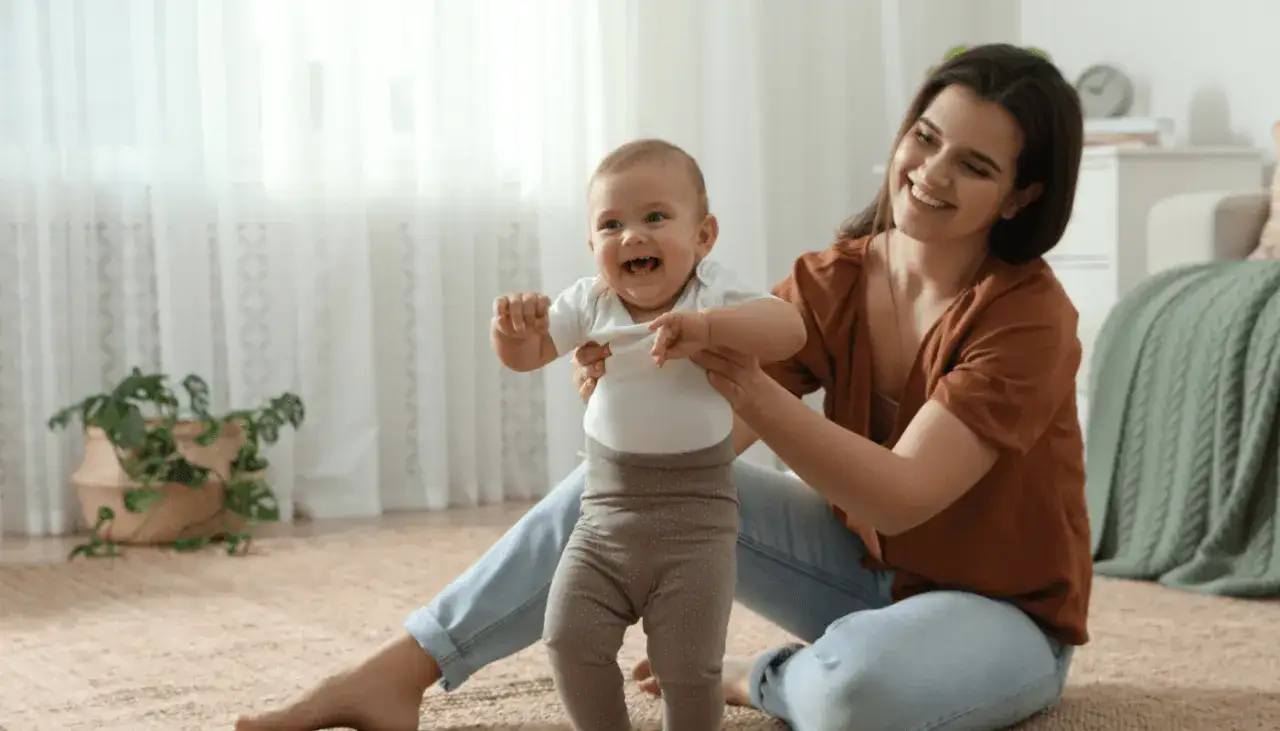 Una madre ayuda a su beb&eacute; a dar sus primeros pasos, capturando una hermosa sonrisa social beb&eacute;.