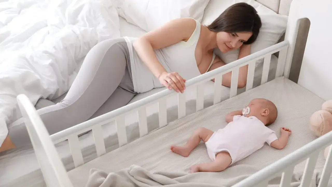 Madre observa tiernamente c&oacute;mo duermen los bebes en su cuna. El beb&eacute;, con un chupete, descansa pl&aacute;cidamente.