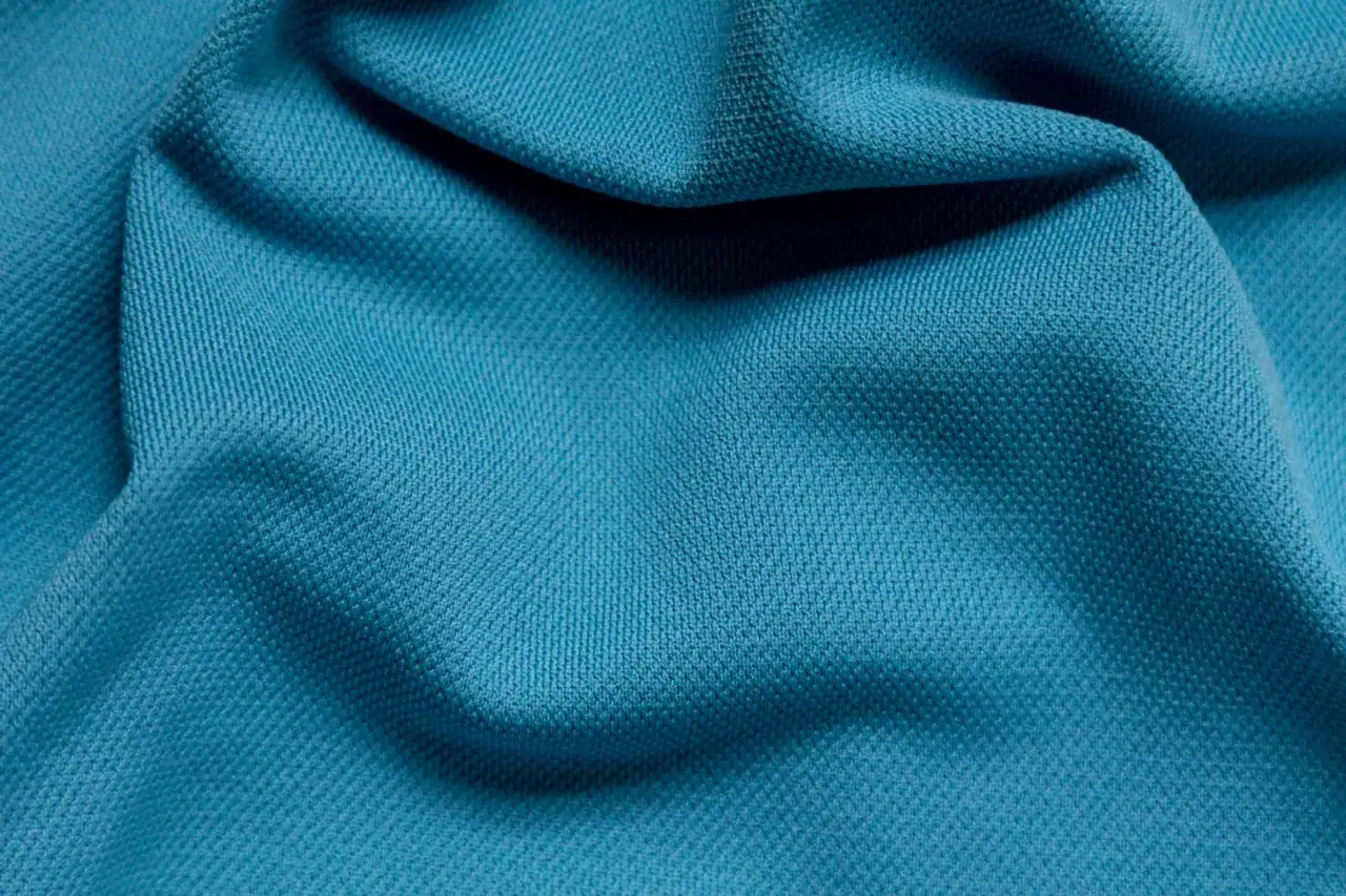 Textura de tela de poli&eacute;ster azul turquesa con pliegues suaves.