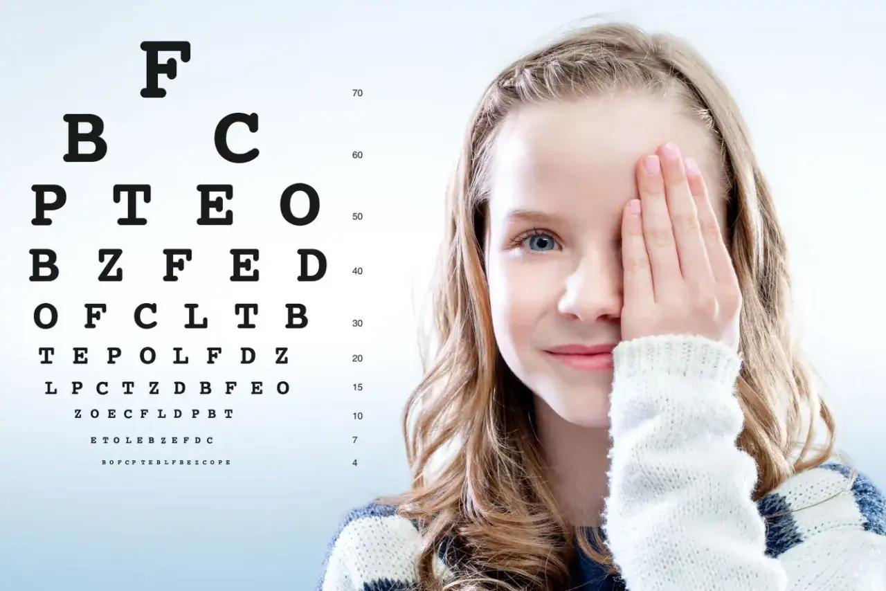 Ni&ntilde;a se cubre un ojo para examen de vista, detectando posible miop&iacute;a infantil.