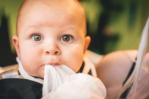 Ojos de bebés antes y después: un primer plano de un bebé con ojos curiosos y una tela blanca en la boca.