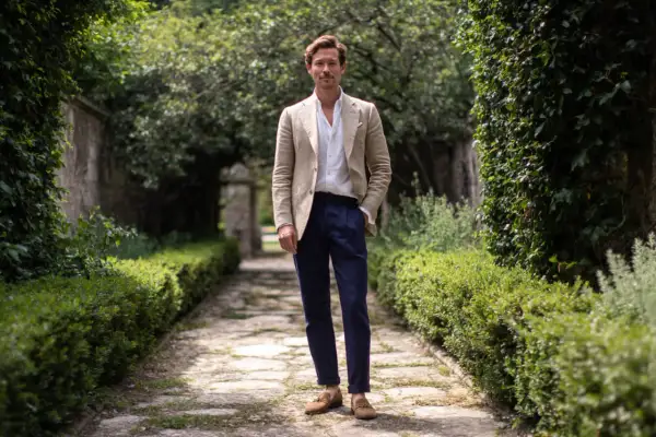 Hombre con chaqueta beige, camisa blanca y pantalón azul marino, ideal para saber como vestir para un bautizo hombre casual.