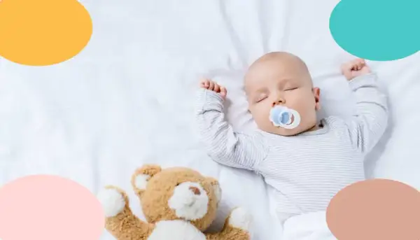 Bebé de 4 meses duerme de lado con chupete y osito.