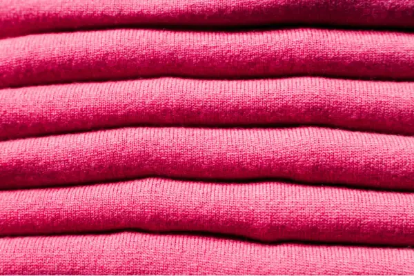 Una pila de ropa de franela rosa, suave y acogedora, lista para abrigarte.