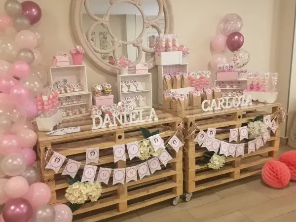 Mesa dulce casera para comunión de niña con globos rosas y blancos, dulces y decoraciones personalizadas. ¡Un festín inolvidable!