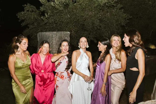 Seis mujeres posan sonrientes, luciendo vestidos elegantes, perfectos para saber como ir vestida a una boda de noche.
